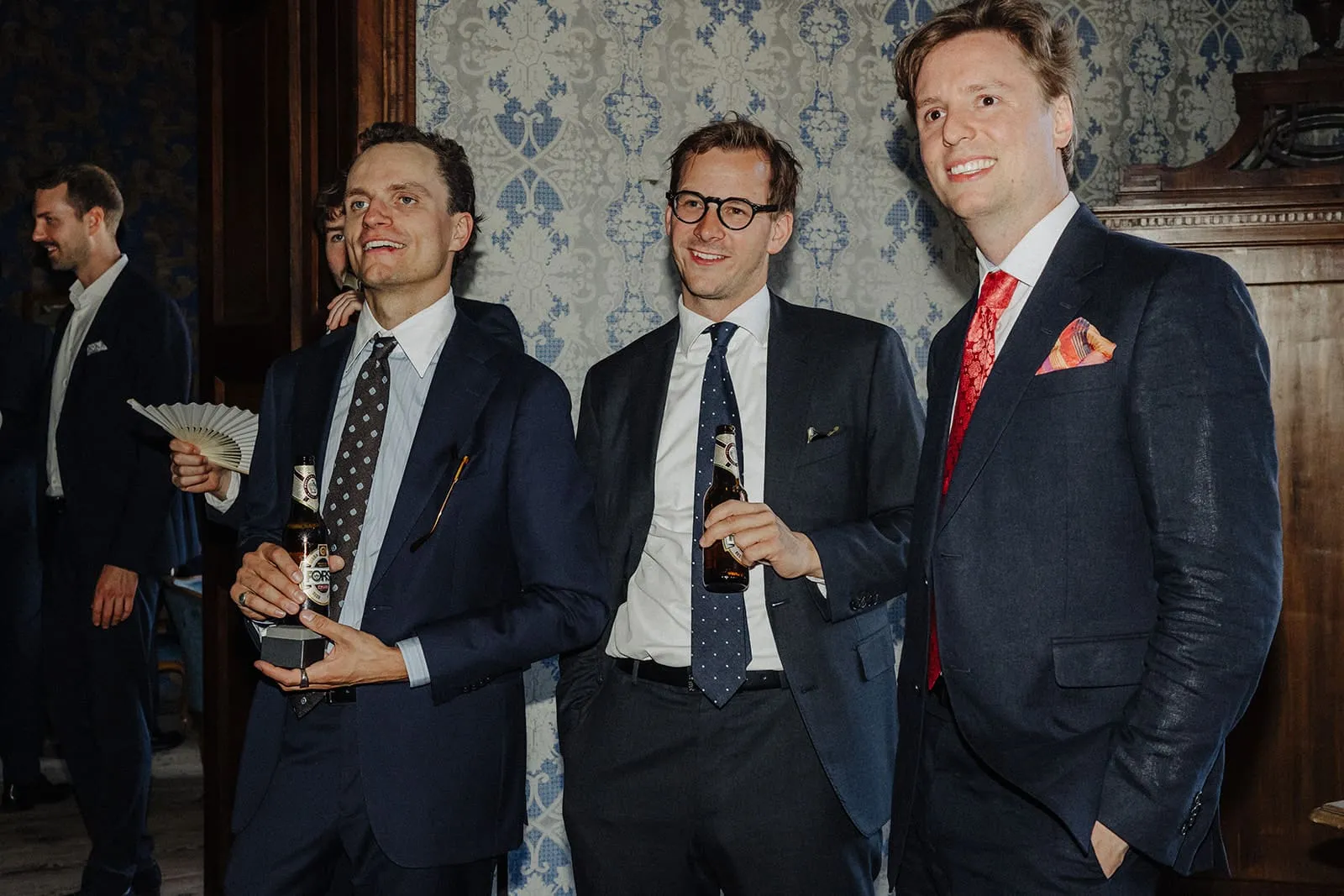 Three guests with beer bottles in front of the patterned wall