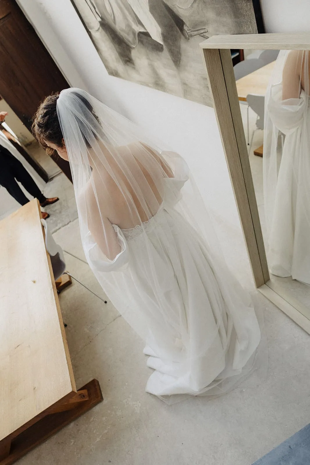 The bride from behind in her veil, the mirror beside her