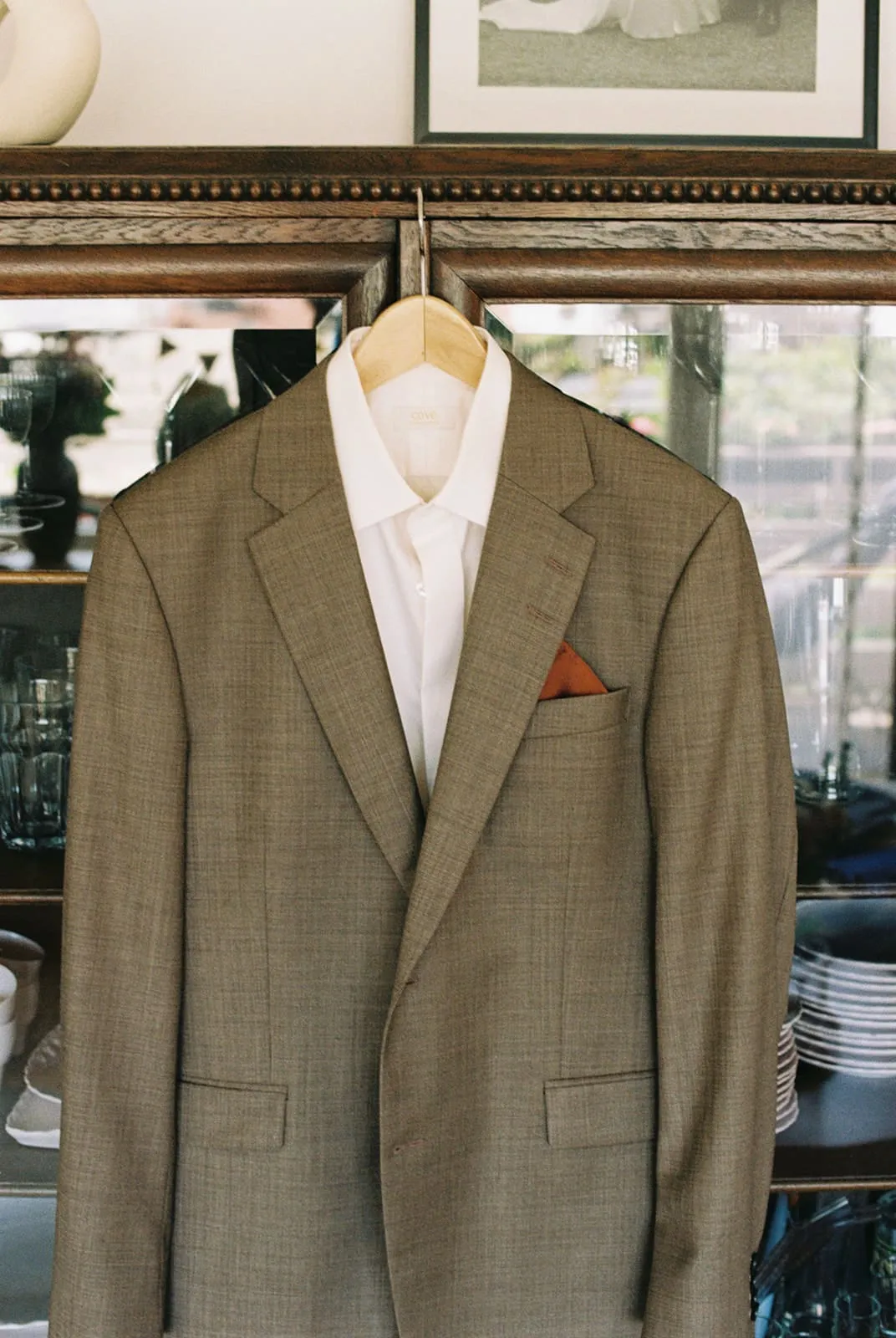 The groom's jacket and shirt on a hanger in front of the old cabinet