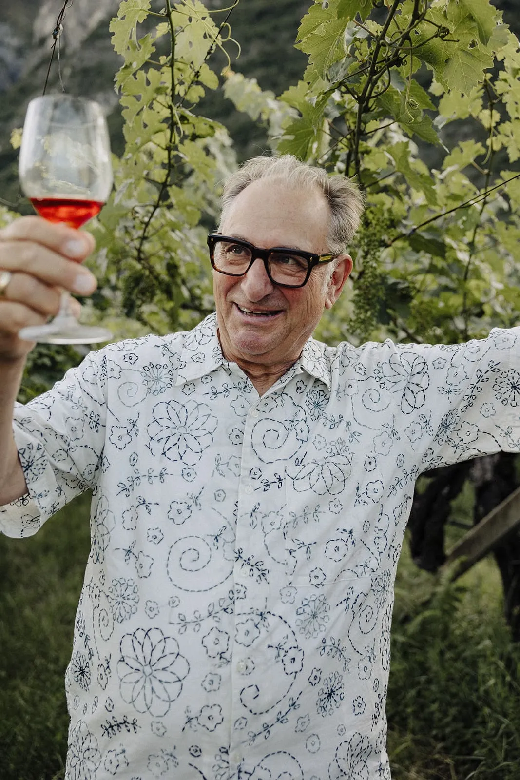 A guest raising a glass of wine under the vines